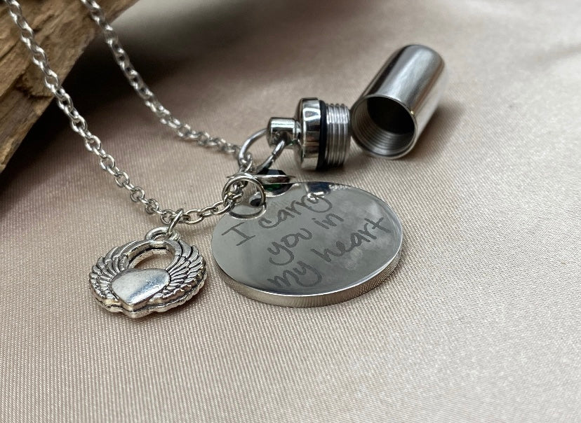 Small Silver Cylinder Cremation Urn Necklace with Angel Wing Charm - Personalized Memorial Jewelry to Hold Human or Pet Ashes, with an Inspirational Charm that Says 'I Carry You With Me