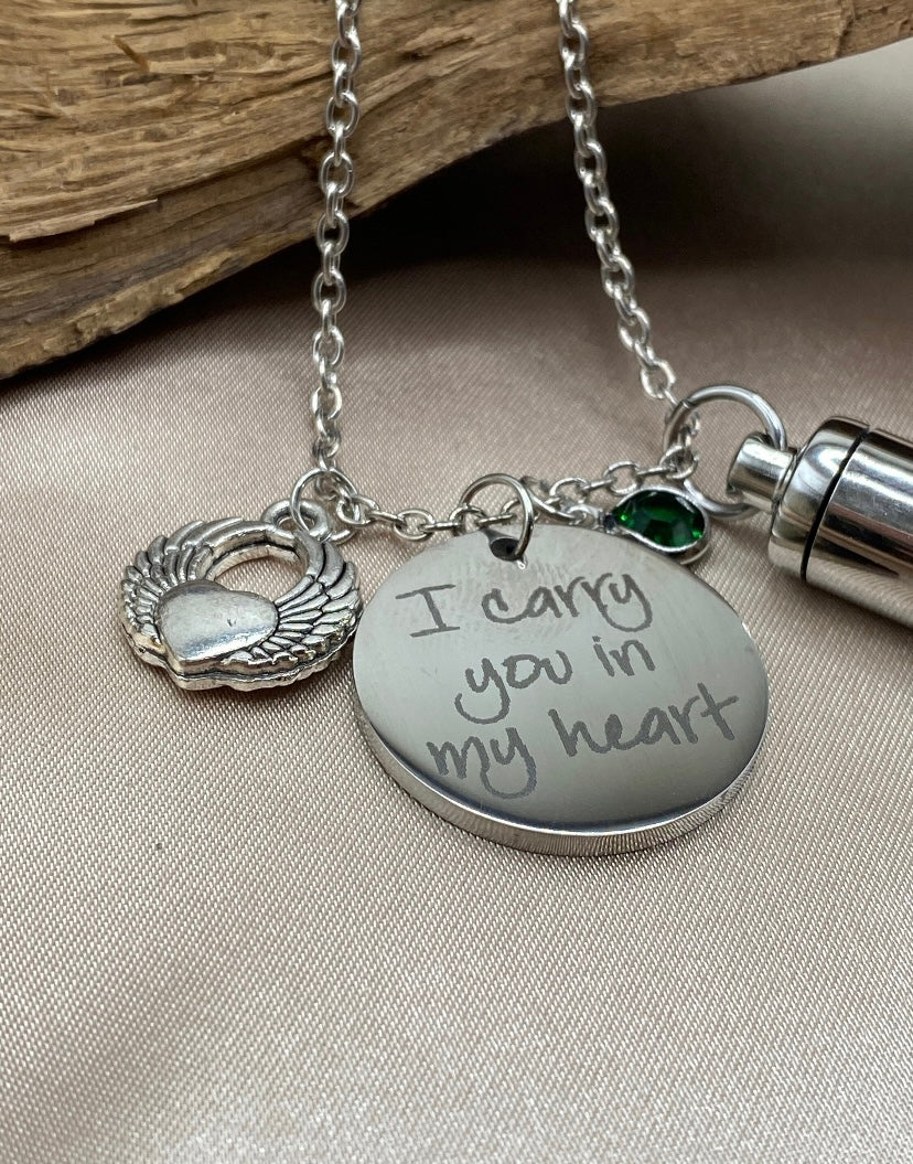 Small Silver Cylinder Cremation Urn Necklace with Angel Wing Charm - Personalized Memorial Jewelry to Hold Human or Pet Ashes, with an Inspirational Charm that Says 'I Carry You With Me