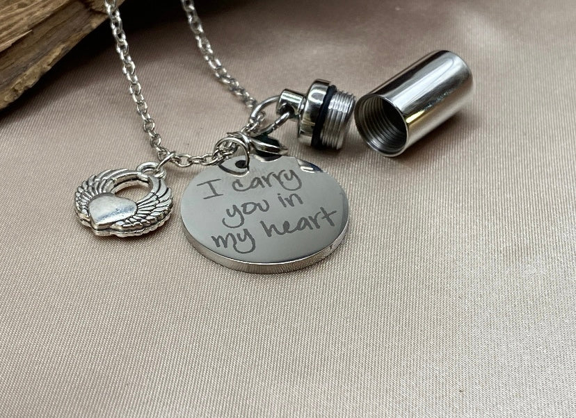 Small Silver Cylinder Cremation Urn Necklace with Angel Wing Charm - Personalized Memorial Jewelry to Hold Human or Pet Ashes, with an Inspirational Charm that Says 'I Carry You With Me