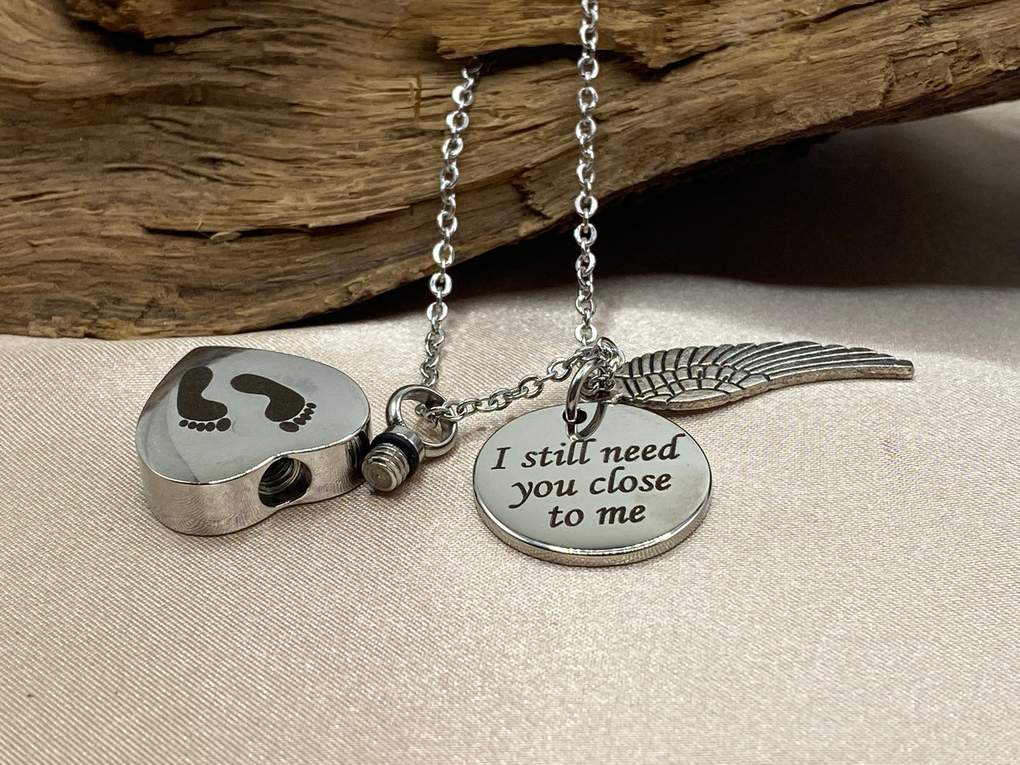 Heart Urn Necklace with Baby Feet Engraved - Stainless Steel Memorial Jewelry with an Angel Wing and an Inspirational Charm Engraved with 'I still need you close to me' - For Holding Human or Pet Ashes